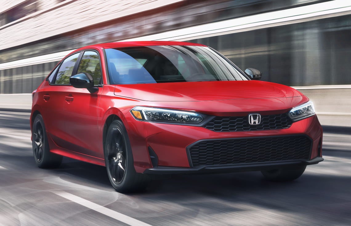Red Honda Civic Sedan driving on a city street, shown from a front three-quarter angle.